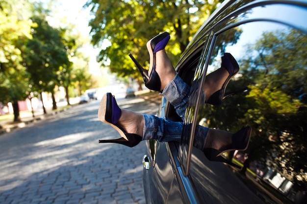 Le gambe della donna fuori dal finestrino dell&#39;auto.