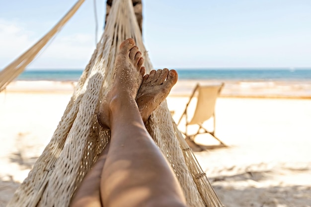 Le gambe della donna nell'amaca contro la vista sull'oceano