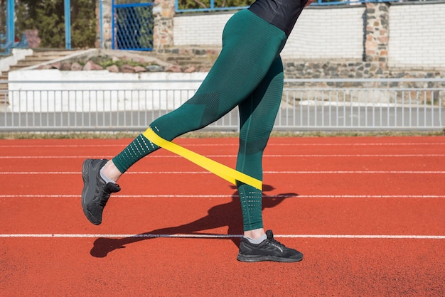 Le gambe della donna si allenano con l'aiuto di un elastico fitness sulla pista rossa.