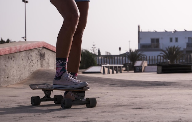 Le gambe della donna skater irriconoscibili si chiudono allo skate park