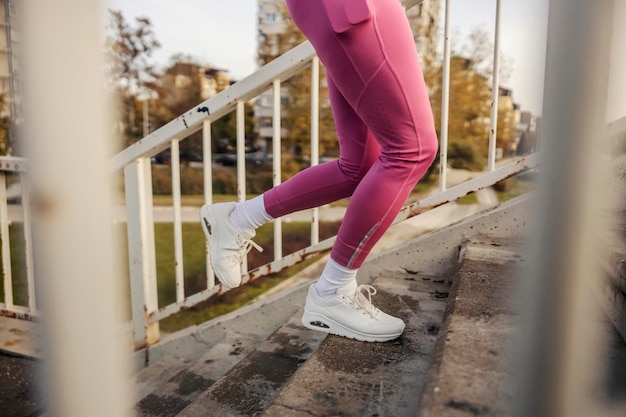 Le gambe di una corridore femminile che sale le scale in un ambiente urbano