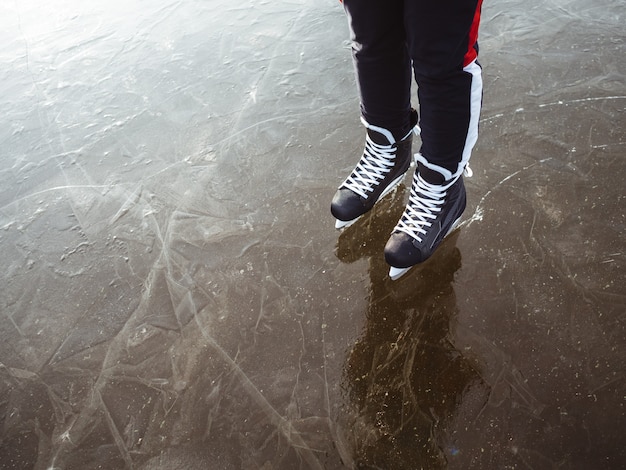 Le gambe di una ragazza in hockey nero pattina sul ghiaccio di un lago