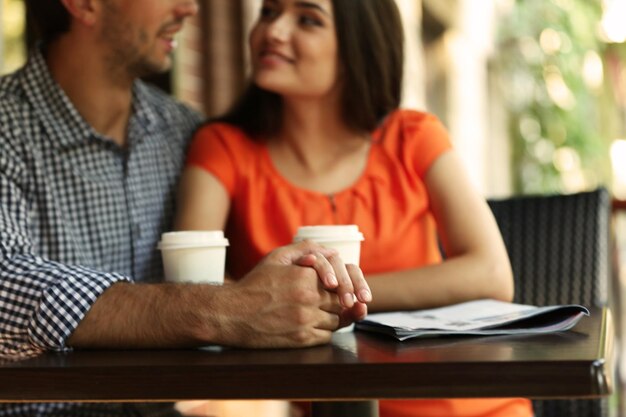 Le giovani coppie bevono il caffè nella caffetteria all'aperto