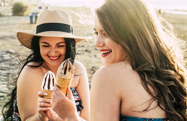 Le giovani coppie di donne formose si godono il gelato e le attività ricreative all'aperto insieme