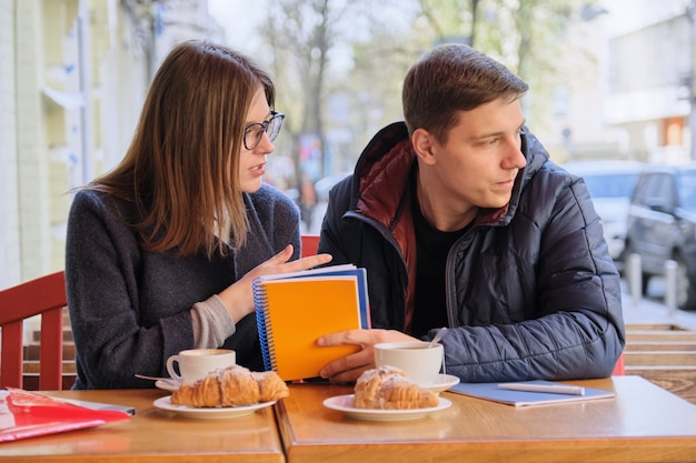 Le giovani coppie di studenti studiano in caffè all'aperto