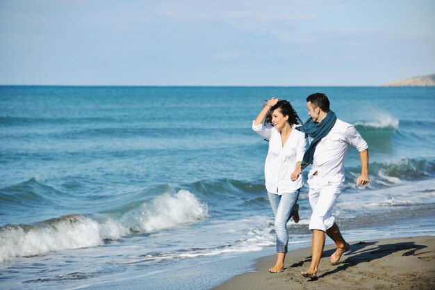 le giovani coppie felici in abiti bianchi hanno una ricreazione romantica e si divertono sulla bellissima spiaggia in vacanza