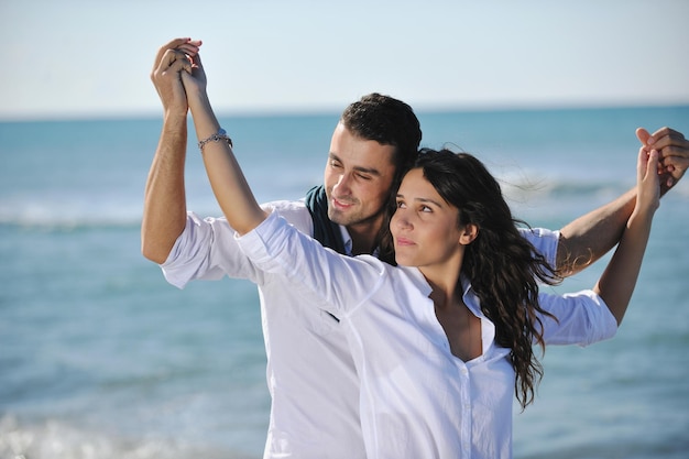 le giovani coppie felici in abiti bianchi hanno una ricreazione romantica e si divertono sulla bellissima spiaggia in vacanza