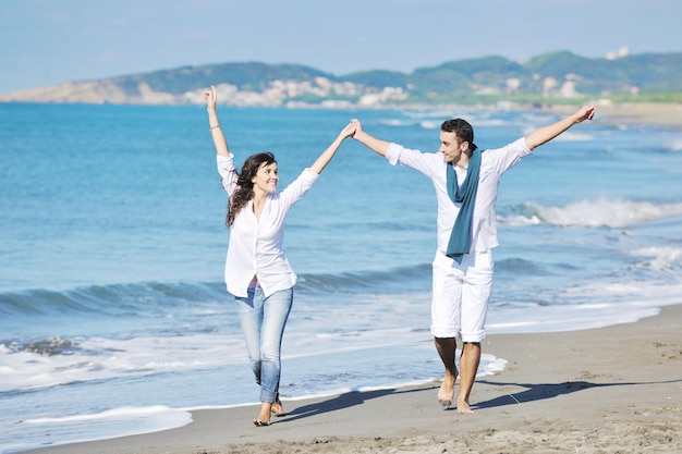 le giovani coppie felici in abiti bianchi hanno una ricreazione romantica e si divertono sulla bellissima spiaggia in vacanza