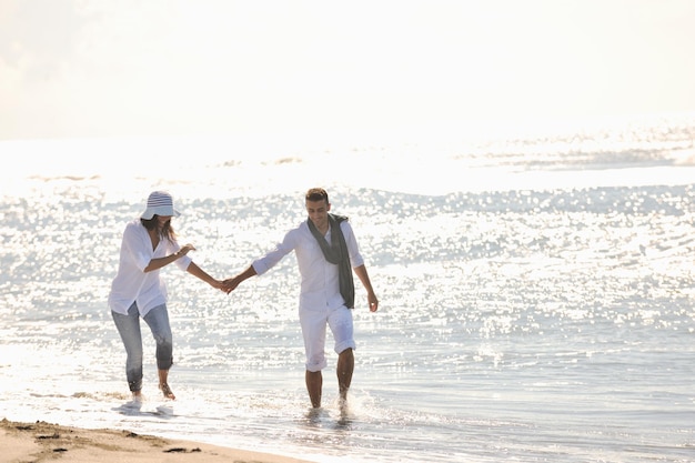 le giovani coppie felici in abiti bianchi hanno una ricreazione romantica e si divertono sulla bellissima spiaggia in vacanza