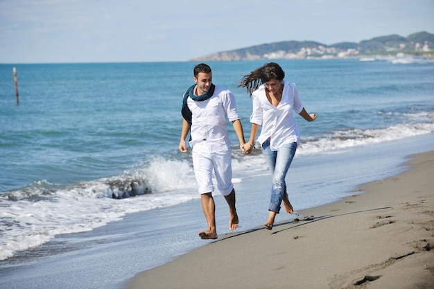 le giovani coppie felici in abiti bianchi hanno una ricreazione romantica e si divertono sulla bellissima spiaggia in vacanza