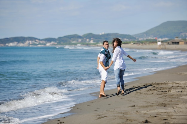 le giovani coppie felici in abiti bianchi hanno una ricreazione romantica e si divertono sulla bellissima spiaggia in vacanza