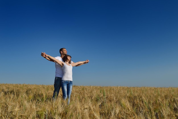 le giovani coppie felici innamorate hanno romanticismo e divertimento al campo di grano in estate