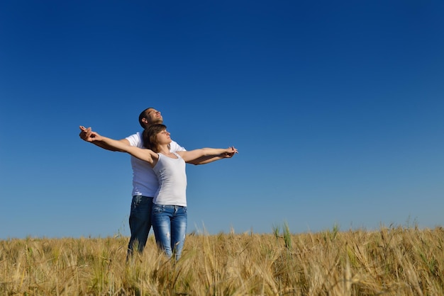 le giovani coppie felici innamorate hanno romanticismo e divertimento al campo di grano in estate