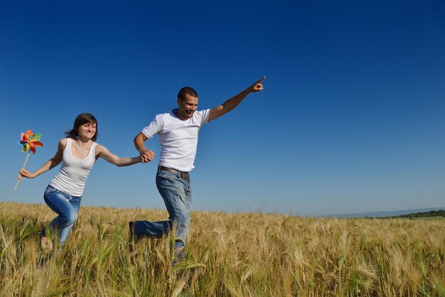 le giovani coppie felici innamorate hanno romanticismo e divertimento al campo di grano in estate