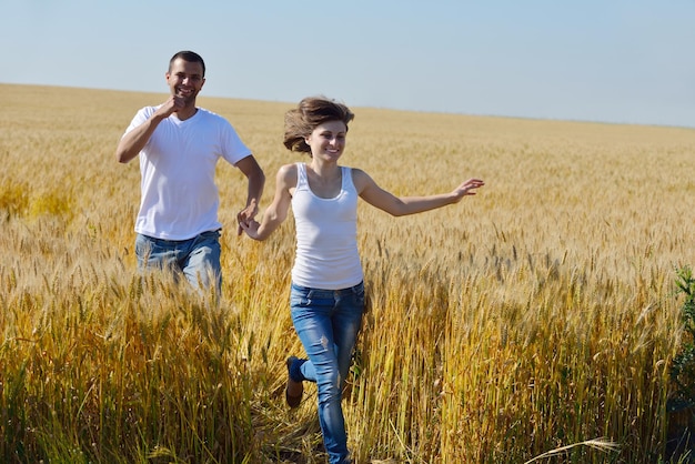 le giovani coppie felici innamorate hanno romanticismo e divertimento al campo di grano in estate