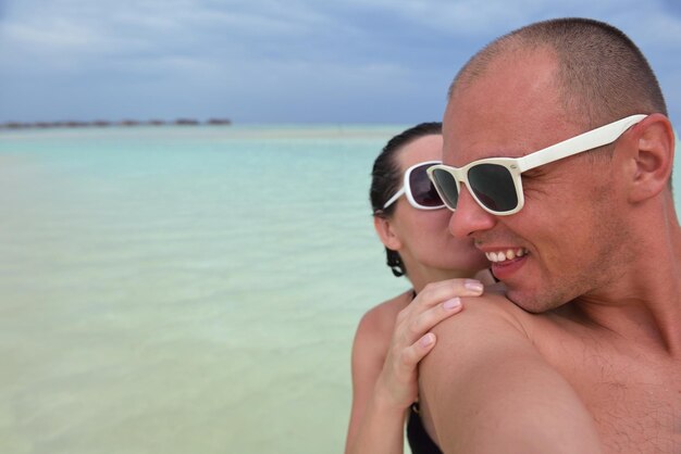 le giovani coppie felici si divertono e si rilassano durante le vacanze estive sullo sfondo Maldive posizione di viaggio e bellissima spiaggia di sabbia bianca