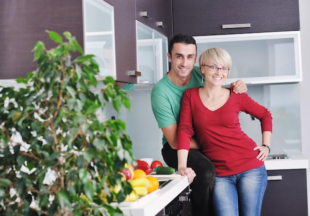 le giovani coppie felici si divertono nella cucina moderna al coperto mentre preparano insalata di frutta e verdura fresca