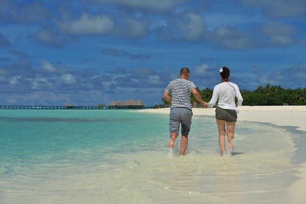 le giovani coppie romantiche felici innamorate si divertono a correre e rilassarsi sulla bellissima spiaggia