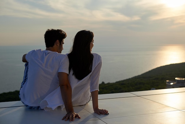 le giovani coppie romantiche felici si divertono a rilassarsi sorridendo al balcone della terrazza all'aperto della casa moderna