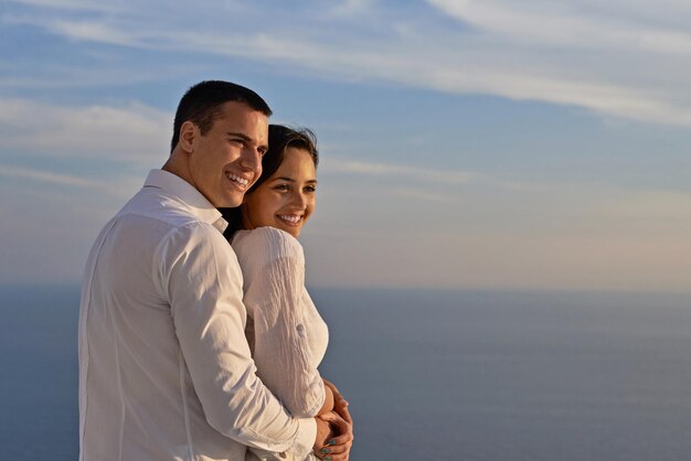 le giovani coppie romantiche felici si divertono a rilassarsi sorridendo al balcone della terrazza all'aperto della casa moderna