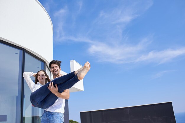 le giovani coppie romantiche felici si divertono a rilassarsi sorridendo alla terrazza del balcone all'aperto della casa moderna