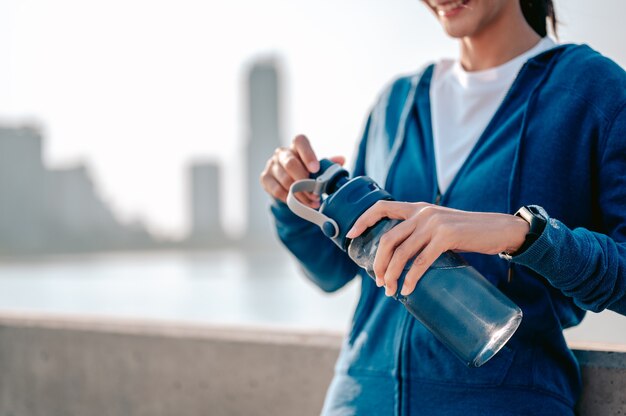 Le giovani donne asiatiche bevono acqua e si riposano dopo aver fatto jogging un allenamento mattutino in città