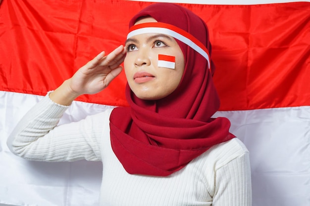 Le giovani donne musulmane asiatiche celebrano il giorno dell'indipendenza indonesiana con lo sfondo della bandiera rossa e bianca