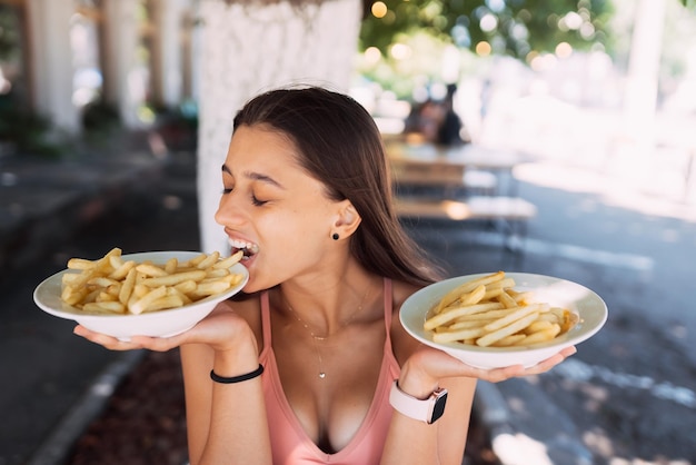 Le giovani donne tengono le patatine fritte su piatti bianchi Street cafe