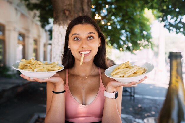 Le giovani donne tengono le patatine fritte su piatti bianchi Street cafe