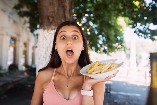 Le giovani donne tengono le patatine fritte su piatti bianchi Street cafe