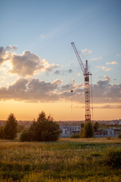 Le gru del grattacielo costruiscono una casa sullo sfondo di un bellissimo tramonto