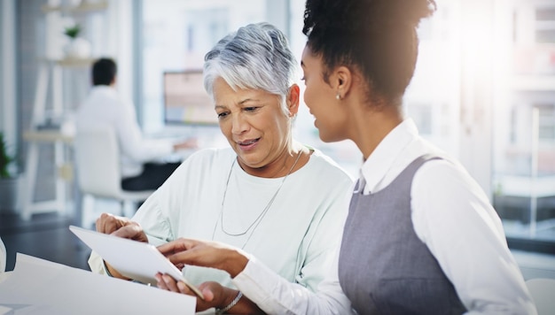 Le idee condivise avvantaggiano un'intera azienda Inquadratura di due donne d'affari che utilizzano insieme una tavoletta digitale in un ufficio moderno