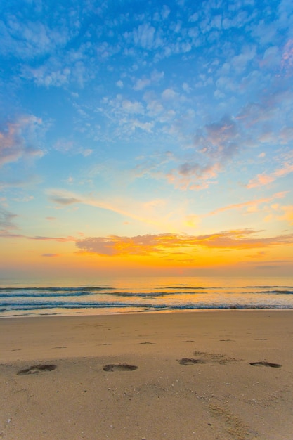 Le impronte sono state mostrate sulla sabbia in vista del mare e del tramonto con il cielo blu