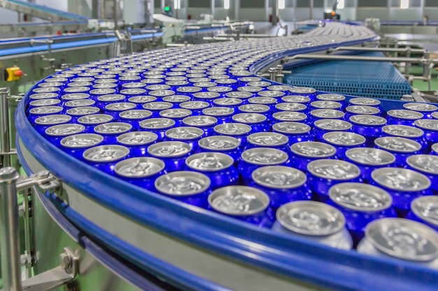 Le lattine per bevande in alluminio per le bevande si muovono sul nastro trasportatore della grande fabbrica.