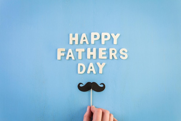 Le lettere di legno non finite firmano la festa del papà su uno sfondo di legno dipinto.