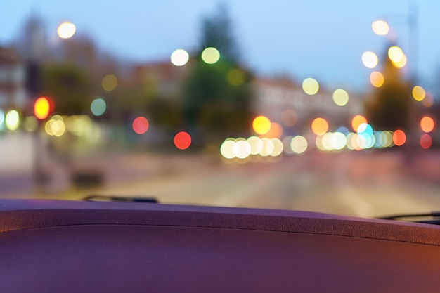 Le luci dell'auto sono sfuocate sulla strada mentre il tramonto entra nella foto della città con copyspace