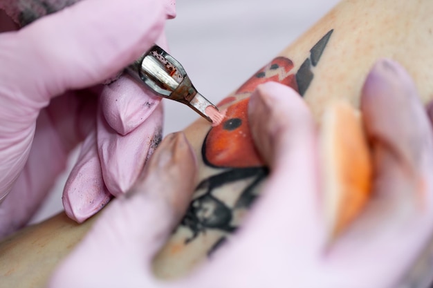 Le macchinette per tatuaggi ad ago iniettano un inchiostro rosso nella pelle di una ragazza