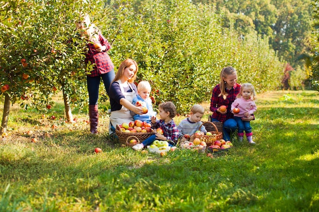 Le madri con bambini in età prescolare nel giardino delle mele educano la natura