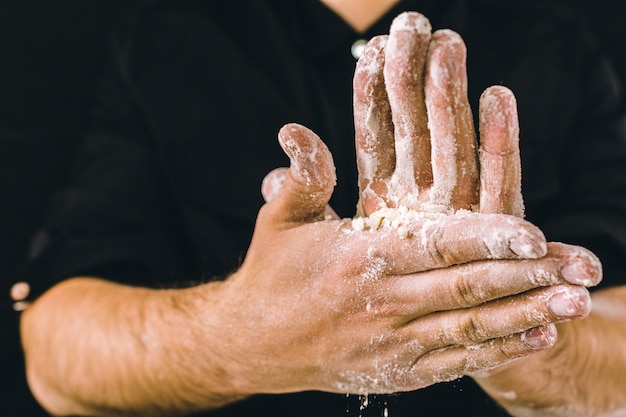 Le mani adulte dell&#39;uomo funzionano con farina, foto scura