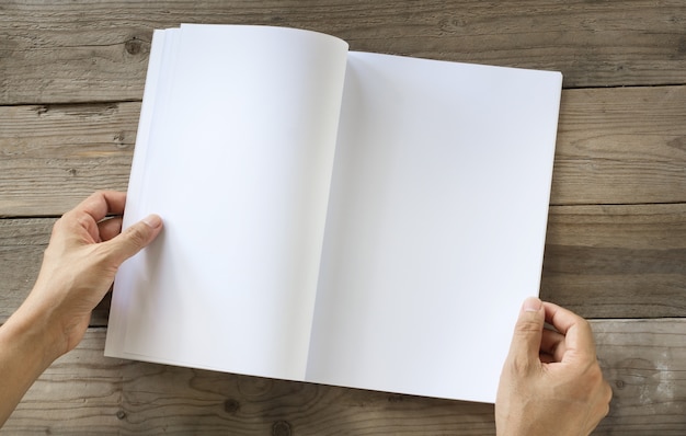 Le mani aprono il catalogo in bianco, riviste, libro mock up sul tavolo di legno