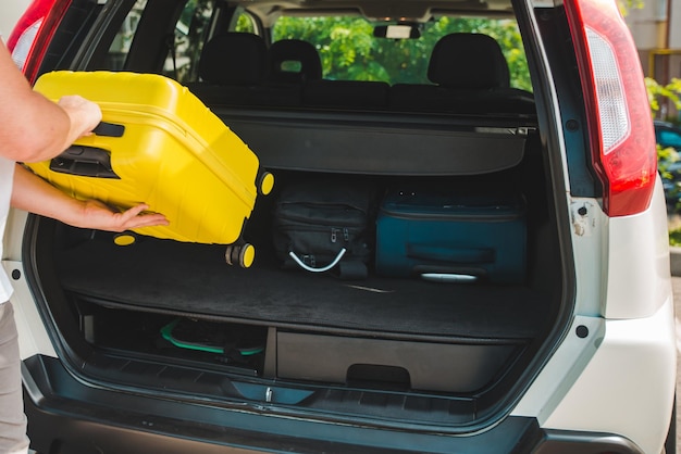 Le mani caricano le borse nel bagagliaio dell'auto concetto di viaggio in auto