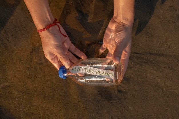 Le mani che tengono una bottiglia di vetro con il messaggio salva il pianeta all'interno del concetto salvano il mondo