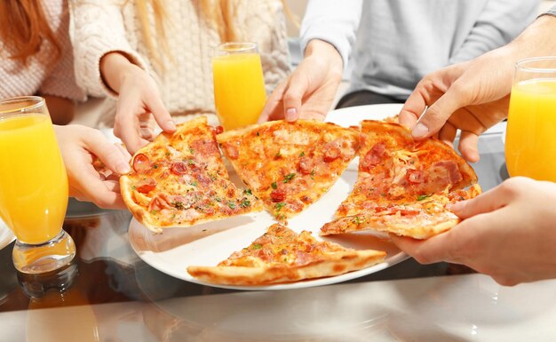 Le mani degli amici che tengono la pizza calda si chiuda