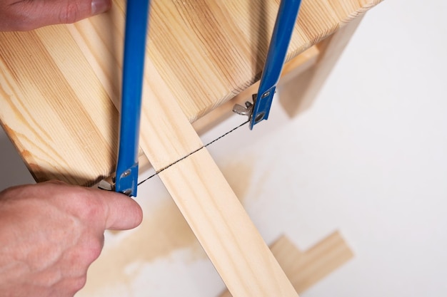 Le mani degli uomini hanno visto con un seghetto alternativo a mano la carpenteria in legno