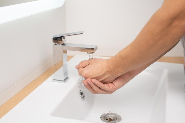 Le mani degli uomini sotto l'acqua corrente nella toilette