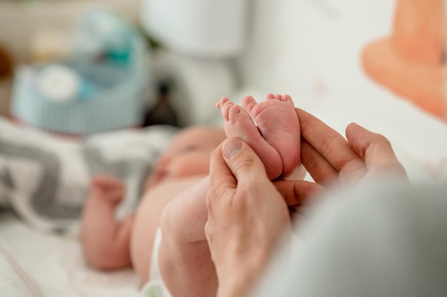 Le mani degli uomini tengono le piccole gambe di un neonato