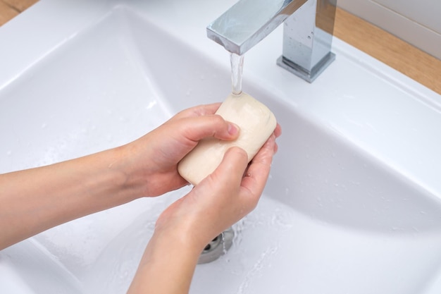 Le mani dei bambini con sapone sotto l'acqua corrente nel lavabo