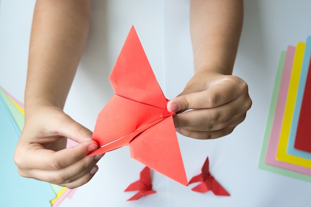 Le mani dei bambini fanno una farfalla origami.