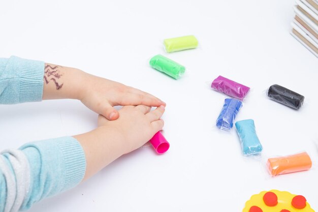 Le mani dei bambini giocano con la pasta per la creatività dei bambini. Gioco da tavolo per lo sviluppo della motricità fine.