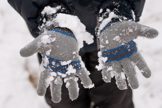 Le mani dei bambini in guanti tutte coperte di neve